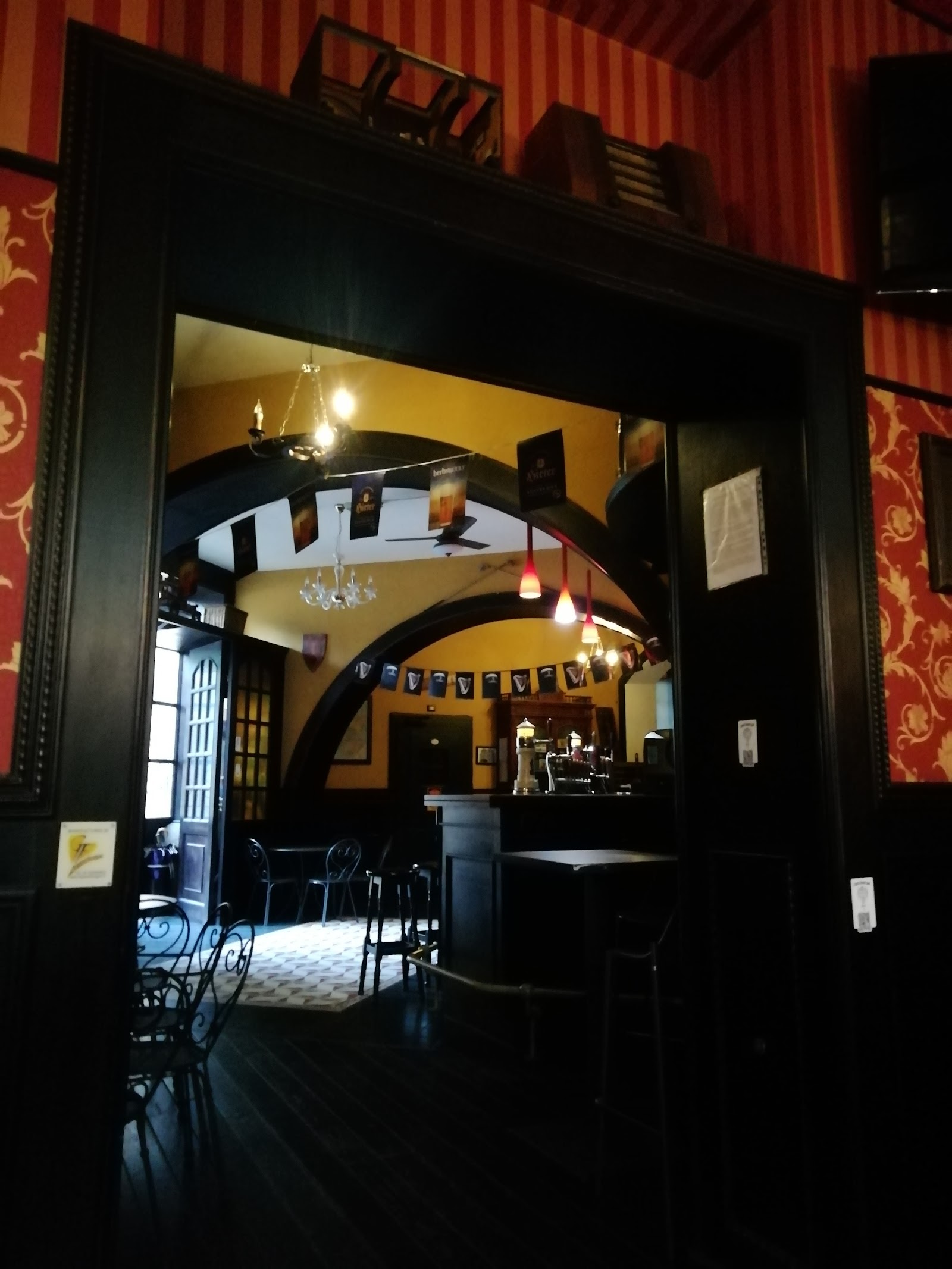 Ingresso del pub con arco in legno scuro e stemmi alle pareti